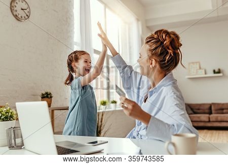 Low Angle Of Excited Small Daughter Giving High Five To Mother And Screaming While Celebrating Succe