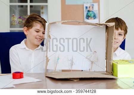 Two Little School Kids Boy Making Paper Doll Theatre. Happy Children And Friends Creating Figures An
