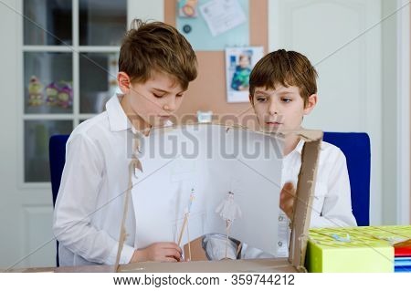 Two Little School Kids Boy Making Paper Doll Theatre. Happy Children And Friends Creating Figures An