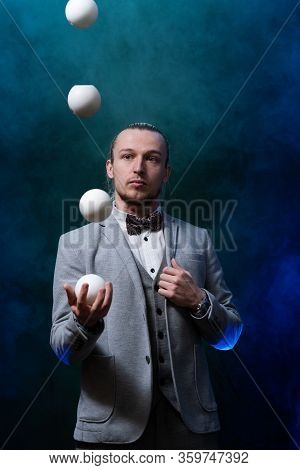 Man Wearing A Black Juggling With White Balls. Management, Control And Success