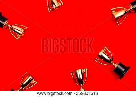 Winner Cups On A Red Background With Copy Space. Flat Lay Style.