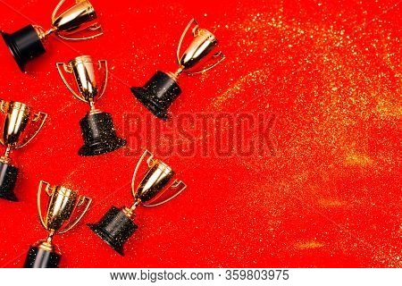Winner Cups On A Red Background With Copy Space. Flat Lay Style.
