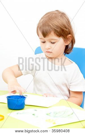 poco ragazza disegna vernice seduto al tavolo
