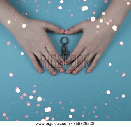 Hands With Fingers In The Shape Of A Heart With A Pink Manium On A Blue Background With Bokeh. Betwe