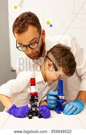 Dad And Son Play With A Microscope In A Makeshift Laboratory