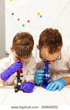 Dad And Son Play With A Microscope In A Makeshift Laboratory