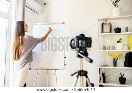 Young Woman Record Tutorial Video How To Learn Foreign Language Online. She Stand Indoors With A Fli