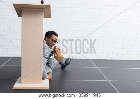 Scared African American Speaker With Paper Bag Having Panic Attack During Business Conference In Off