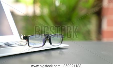 Spectacles On Top Of Computer Laptop With Home And Green Nature Background. Copy Space. Work Remotel