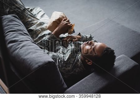 African American Soldier In Military Uniform Holding Paper Bag While Having Panic Attack And Sufferi