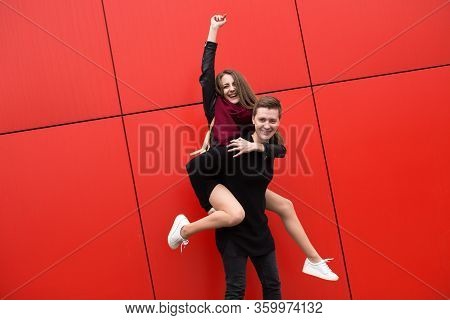 Happy Young State Of Paran The Red Background Of The Wall, The Girl Jumps On Guy