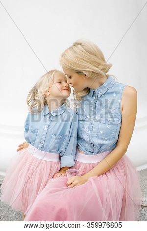 A Beautiful Young Blonde Mom And Her Charming Daughter In The Same Romantic Clothes Are Kissing. Hap