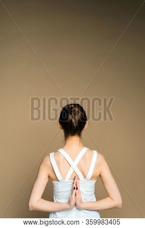 A Woman Holds Her Hands Behind Her Back And Practices Yoga On A Beige Background. A Beautiful Young 