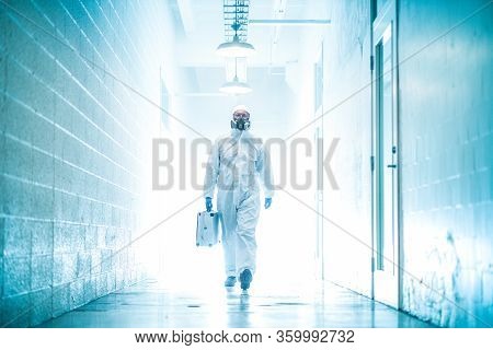 Corona Virus Concept. Male Doctor Waliking In Coridor With Biohazard Case