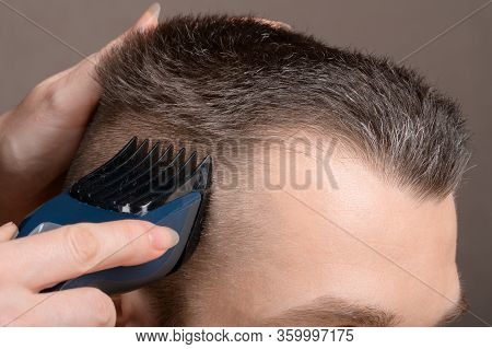 A Barber's Hand With A Young Man's Hair Clipper. Creating A Stylish Men's Haircut In A Barbershop. M