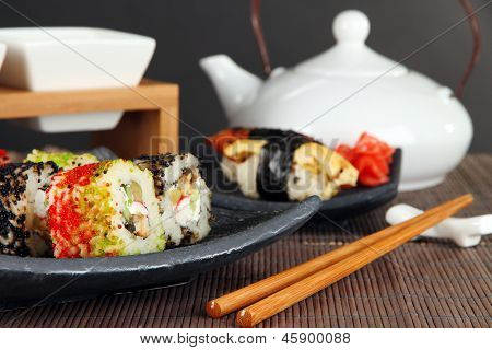 Velsmagende Maki sushi - Roll på grønne blade på bordet på grå baggrund