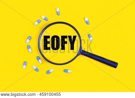 Pharmaceutical Tablets And Capsules Near A Magnifying Glass With The Text Eofy On A Yellow Backgroun
