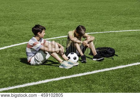 Teenage Boy Comforting Consoling Upset Sad Friend In School Stadium. Education, Bullying, Conflict, 
