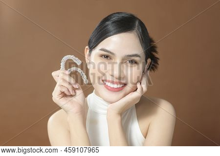 A Young Woman With Beautiful Teeth Is Holding Invisalign, Healthy Dental Concept