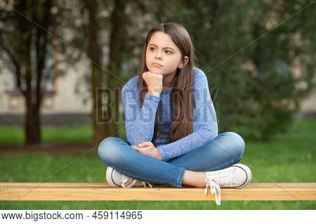 Thinking Teenage Girl Thinking While Sitting Legs Crossed On Bench Outdoors, Thinking