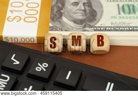Business Concept. On The Table Are Dollars, A Calculator And Cubes With The Inscription - Smb