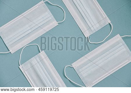 Tipical Surgical Masks With Rubber Ear Straps On Blue Background, Top View . Protection Concept.