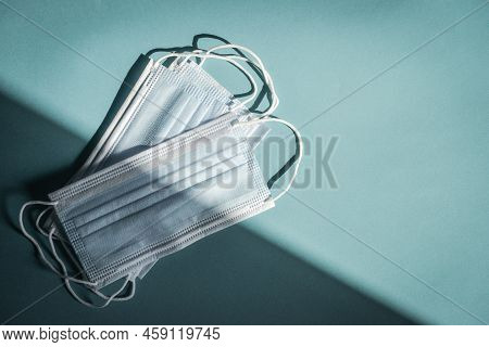 Tipical Surgical Masks With Rubber Ear Straps On Blue Background, Top View . Protection Concept.