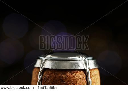 Sparkling Wine Cork With Muselet Cap Against Blurred Festive Lights, Closeup. Space For Text