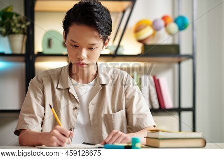 Portrait Of Serious Teenage Boy Sitting At Desk Concentarted On Solving Equations
