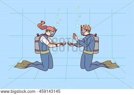 Divers In Uniform In Swimming Pool. Man And Woman Diving Underwater With Tubes Having Lesson Togethe
