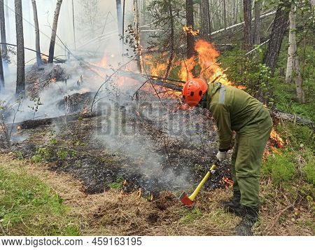 Man Digging A Mineral Strip, Putting Out A Fire In The Forest. Forest Fire Extinguishes. Forest Burn