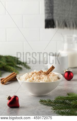 Scandinavian Rice Porridge With Cinnamon In A Bowl Surrounded By Christmas Balls. Breakfast On Chris