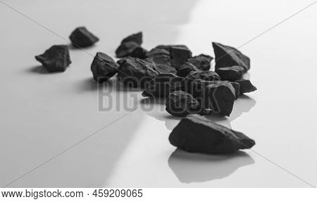 Shungite Stones On A White Background With Shadows With A Copy Of The Space.