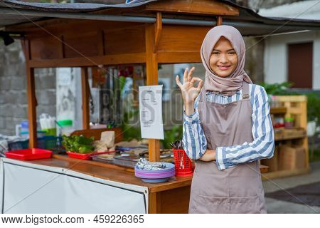 Woman Standing In Front Of Her Small Traditional Food Shop And Showing Thumb Up