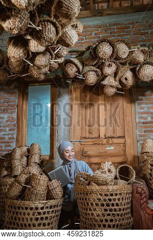 Female Entrepreneur In Hijab Squatting Holding Tablet On Craft House