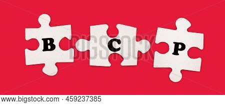 Three White Jigsaw Puzzles With The Text Bcp Business Continuity Plan On A Bright Red Background.