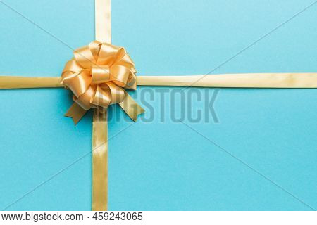 Top View Of Gold Ribbon Rolled And Yellowbow Isolated On Colored Background. Flat Lay With Copy Spac
