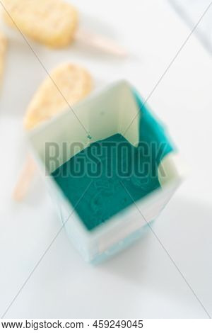 Dipping Frozen Cakesicles Into Melted Chocolate To Prepare Mermaid Cakesicles.