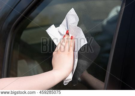 Woman Wipes Car Glass With Paper Napkin, Glass In Spray Drops, Reflection On Glass. Car Service Outd
