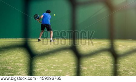 Padel Player With Black Racket Playing A Match In The Open Behind The Net Court