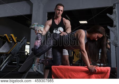 Fitness Woman Doing Donkey Kicks Exercise With Guidance Of Her Personal Trianer