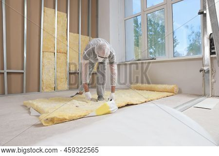 Worker Measuring And Cutting Insulation Material Indoors