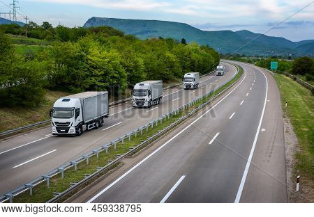 Four White Trucks In Line On A Country Highway