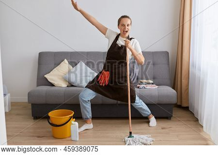 Image Of Happy Young Woman Singing While Washing Floor In Living Room, Using Wet Moist Mop As Microp