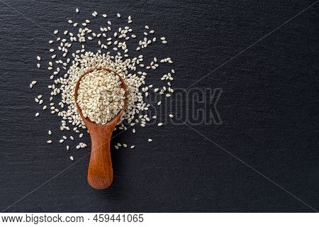 Raw Sesame Seeds In A Wooden Spoon Over Black Slate Background. Sesamum Indicum For Healthy Eating A