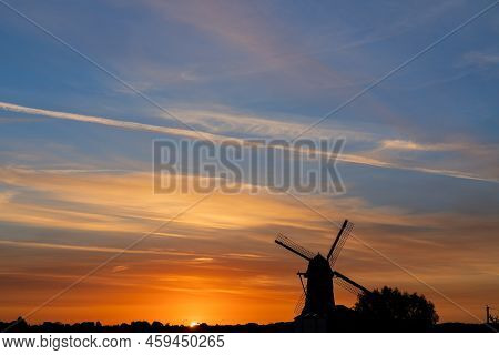 Early In The Morning There Is A Beautiful Windmill Whit The Sun Rising In The Sky