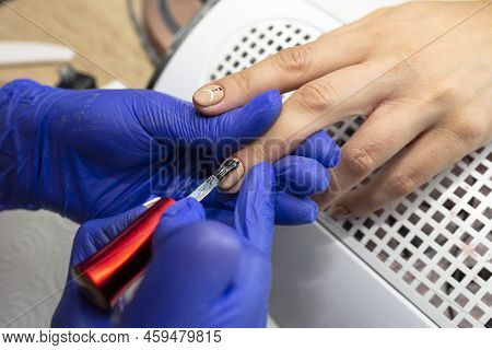 The Manicurist Applies A Topcoat To The Finished Hybrid Nails With A Brush.