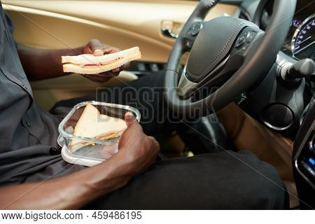 Close-up Image Of Taxi Driver Sitting In Car And Eating Sandwich For Luch
