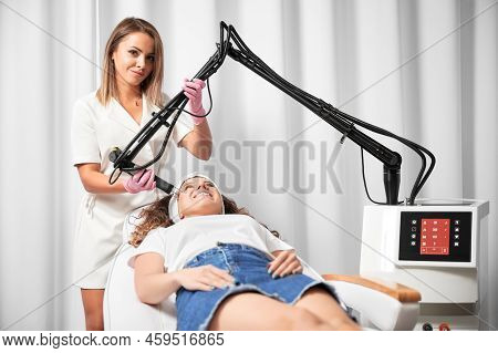Female Doctor Cosmetologist Using Erbium Ablative Laser Machine While Performing Resurfacing Procedu