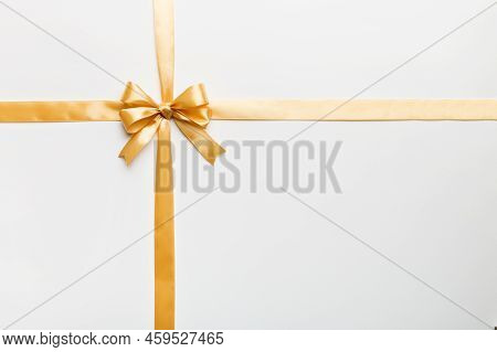 Top View Of Gold Ribbon Rolled And Yellowbow Isolated On Colored Background. Flat Lay With Copy Spac